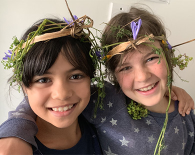 Two children wear crowns made from flowers and leaves.