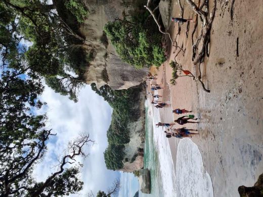 Groups of people walking along a cliff-hugging beach. 
