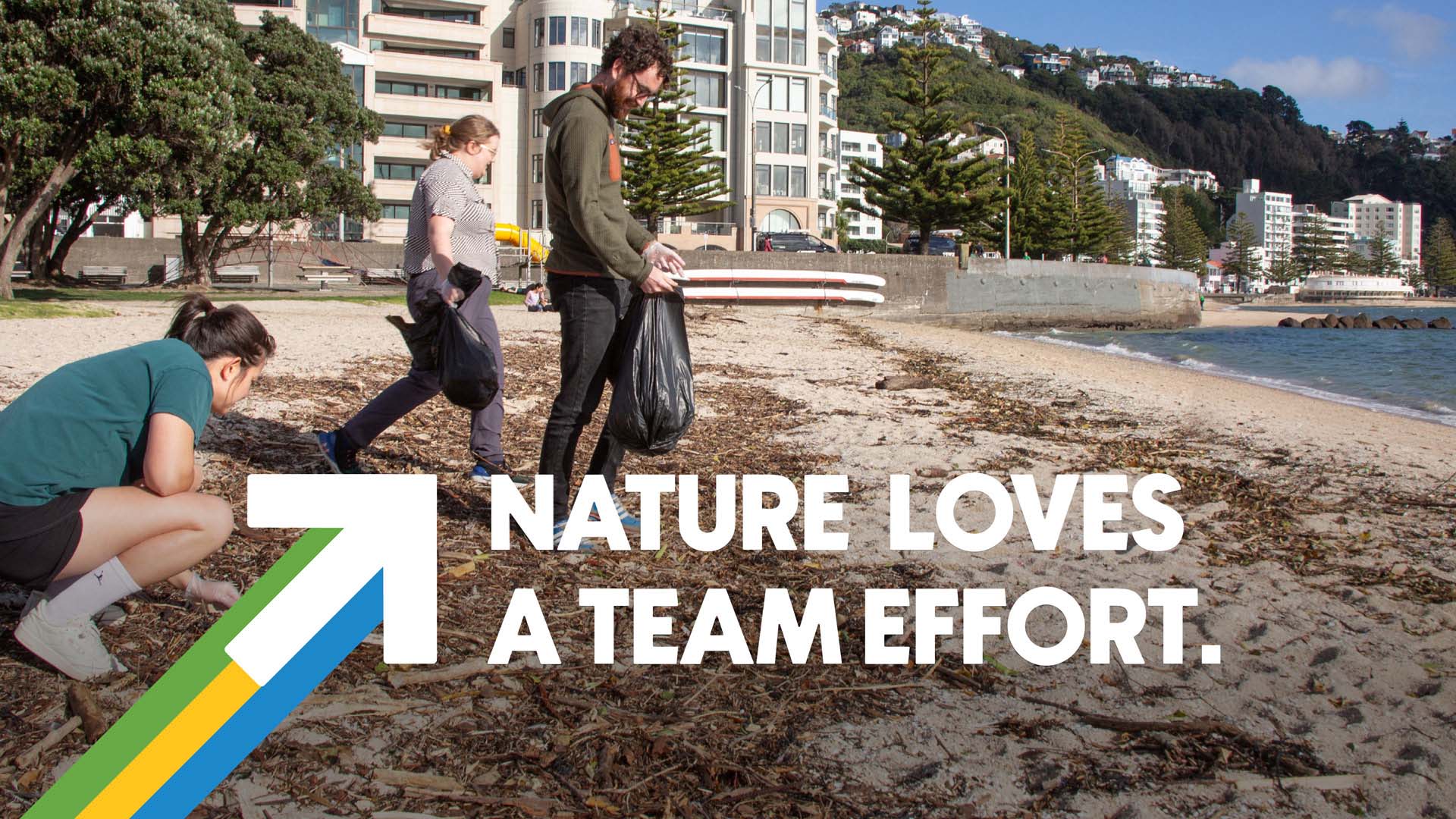 Three people collecting rubbish on an urban beach. The text 'Nature loves a team effort' is superimposed over the image.