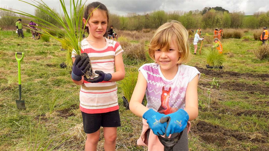 Two children work together on planting.