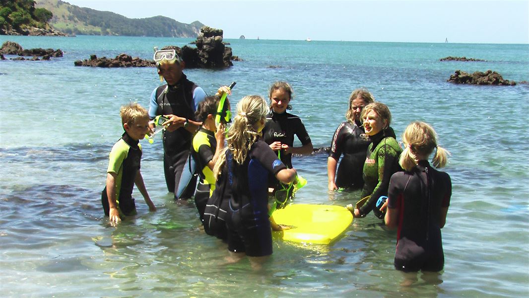 Instructor and school children in water. 