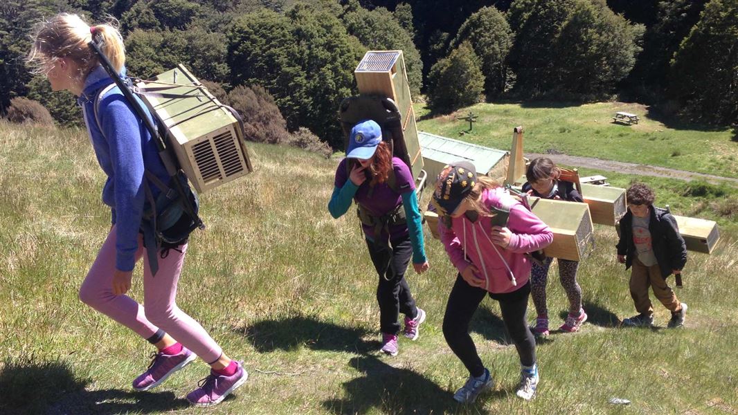 A group of young female students carrying traps up a hill