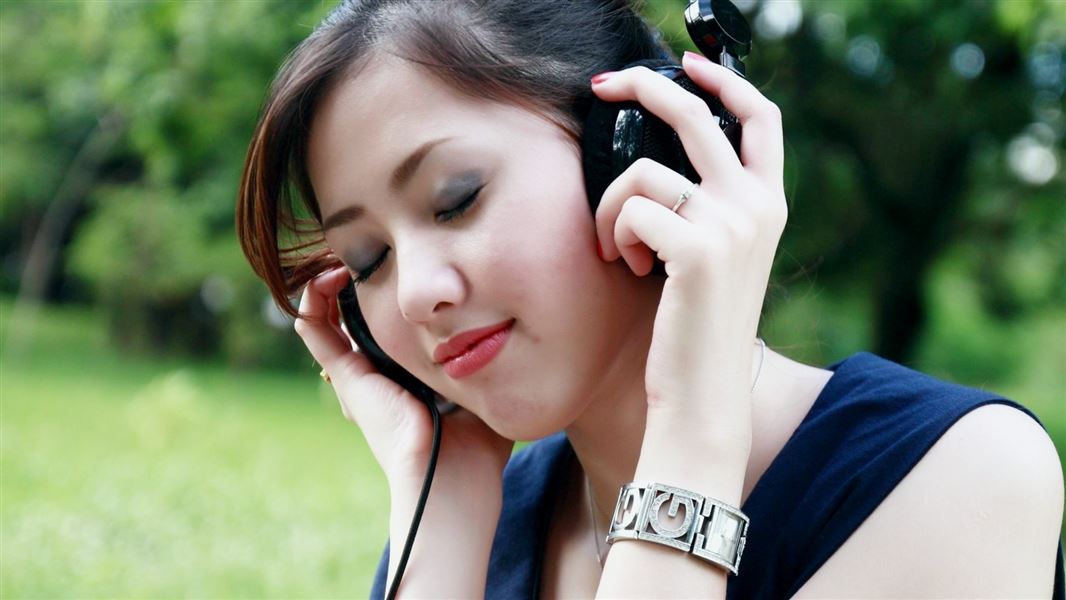 A woman listening to headphones outdoors.