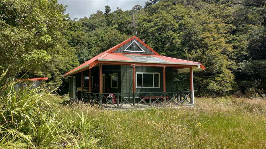 Mitre Flats Hut in a grassy clearing.