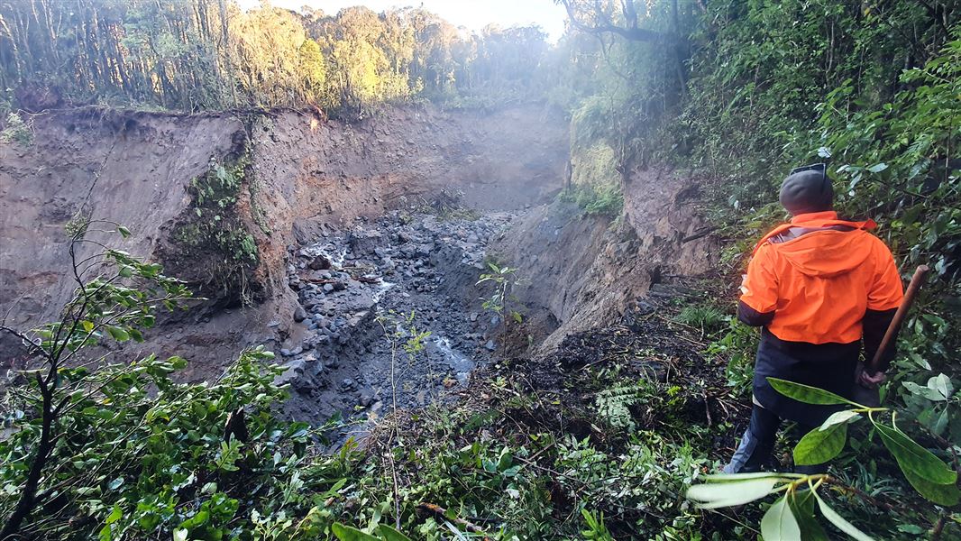 Person in high-vis jacket looks at damaged land.