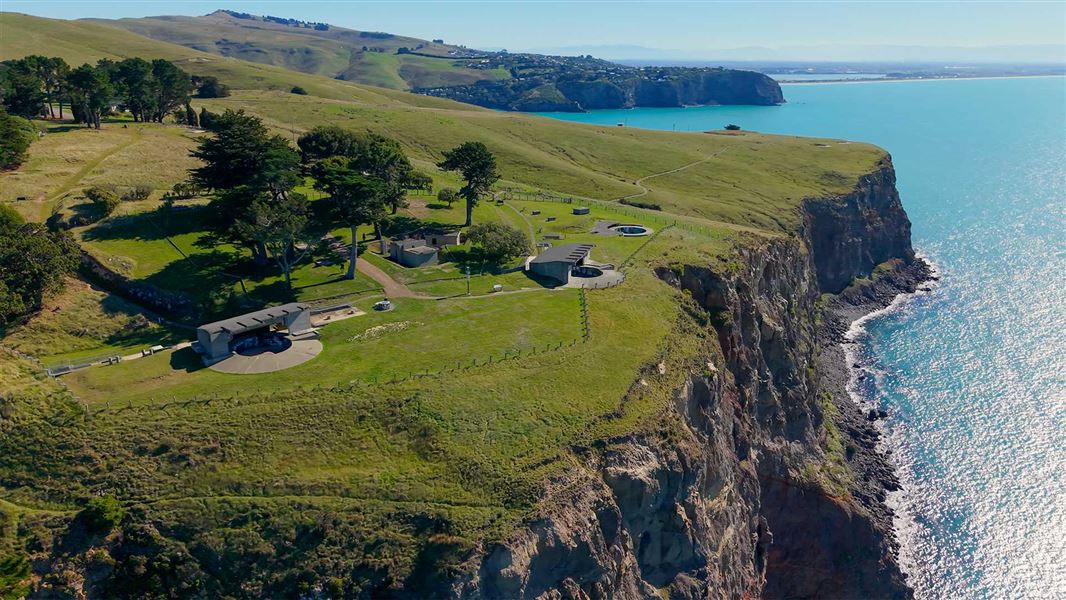 Aerial view of a grassy headland with sheer coastal cliffs dropping to the sea. 