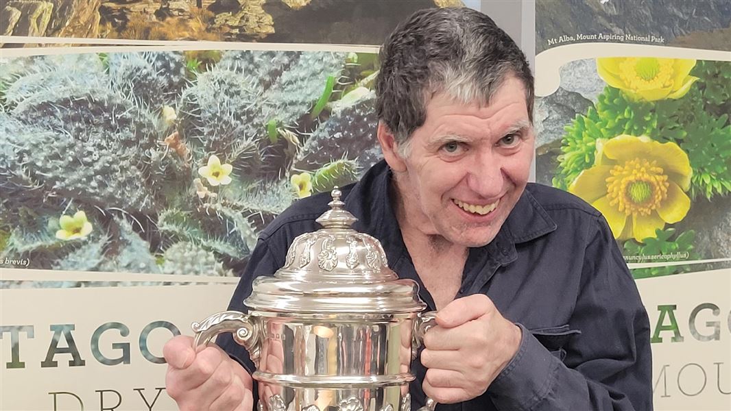 Award winner holding silver cup. 