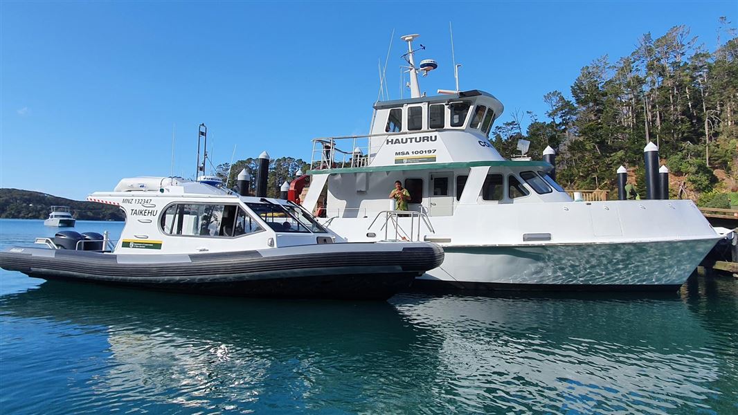 Two large boats with DOC logos sitting at a wharf.