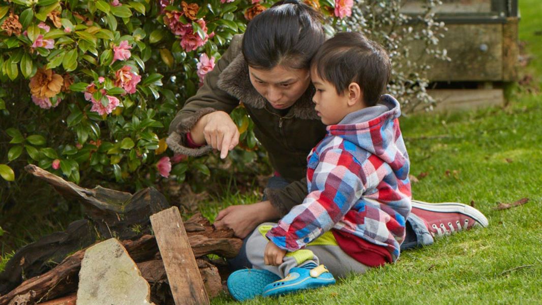 Mother and child looking at a lizard in backyard.
