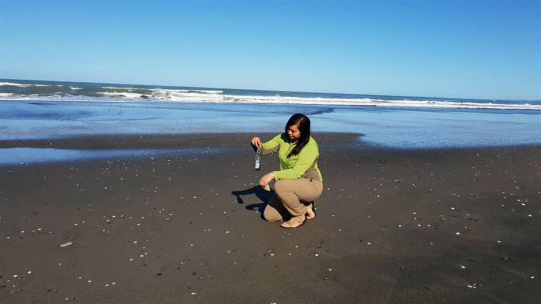 Ranger Jaycee Tipene Thomas holding plastic found on the beach.