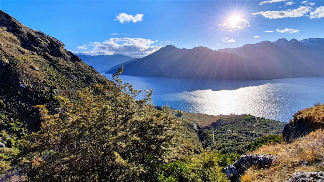 A large lake surrounded by mountains and small streams going towards the lake.