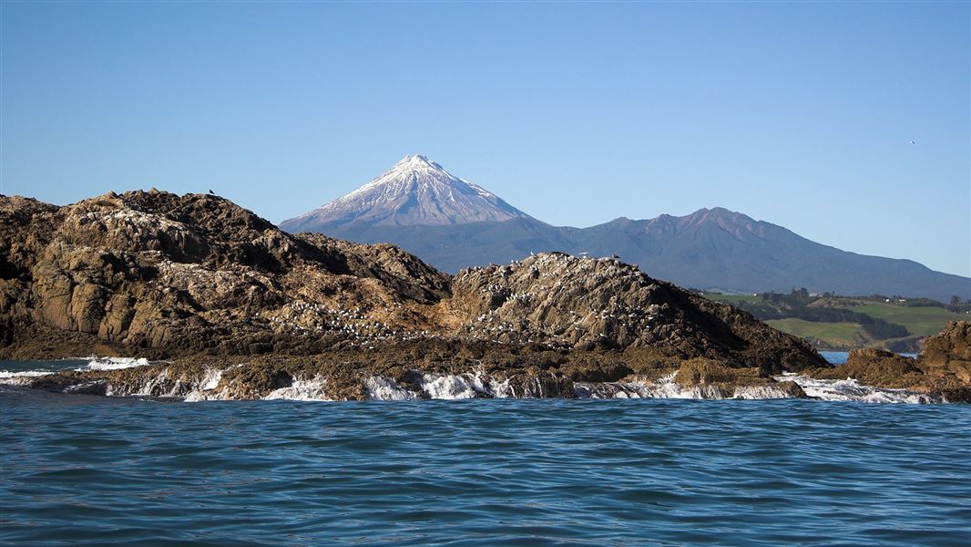 View of Waikaranga Seal Rock, with Mount Taranaki in the background