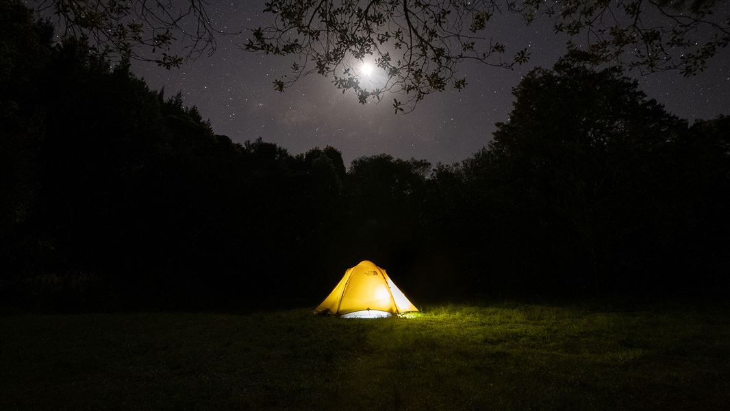 Yellow tent under starry night sky.