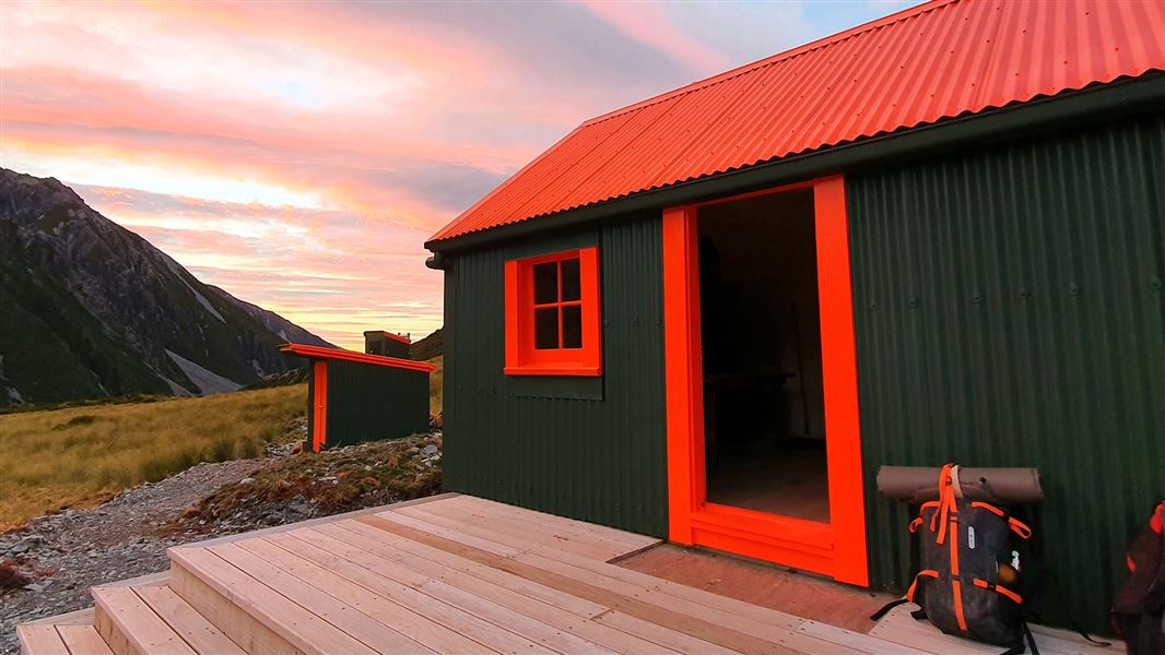 Green building with red roof near hills.