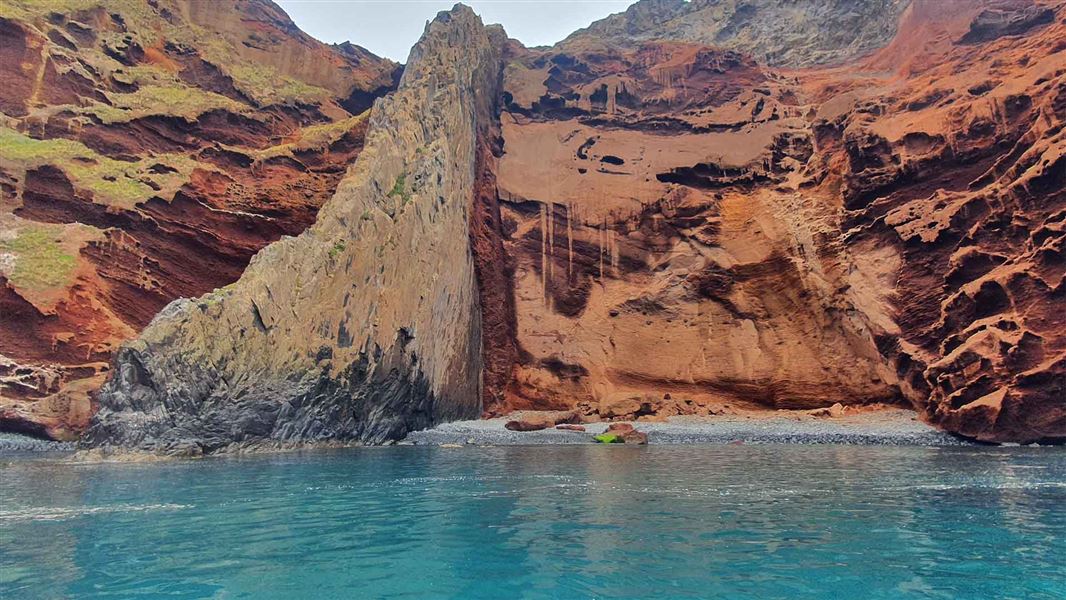 A small sea inlet that leads to orange rocked cliffs.