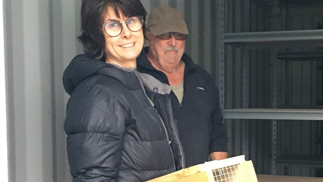 Two people standing together holding a wooden trap.