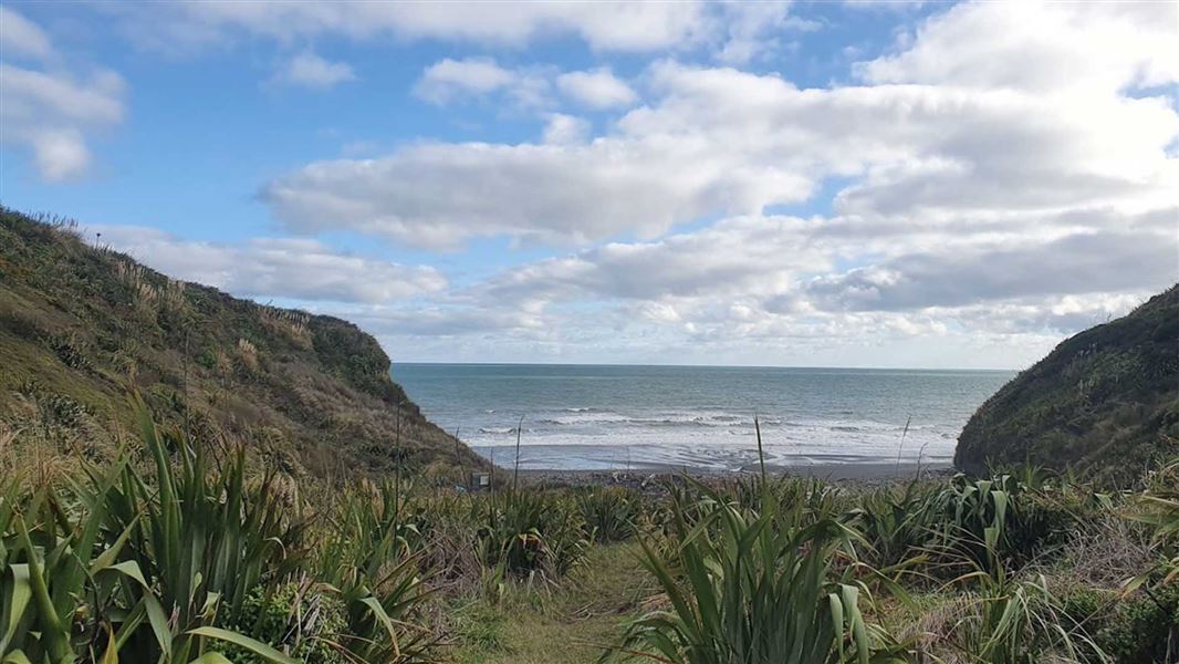 View from the top of a hill looking down into a bay flanked by high cliffs.