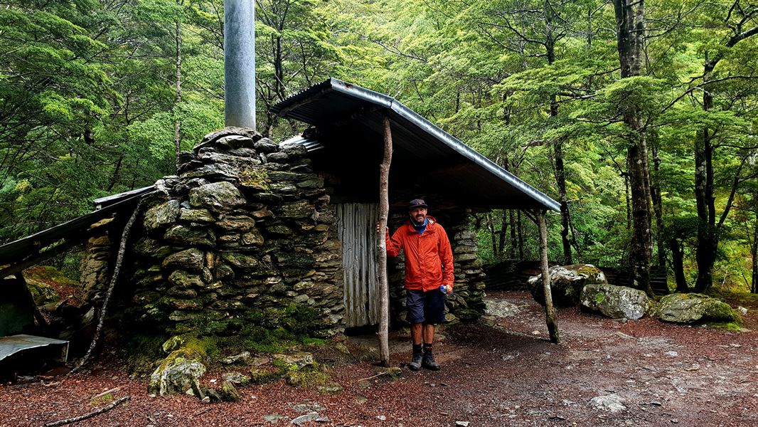 Person standing in front of small building.