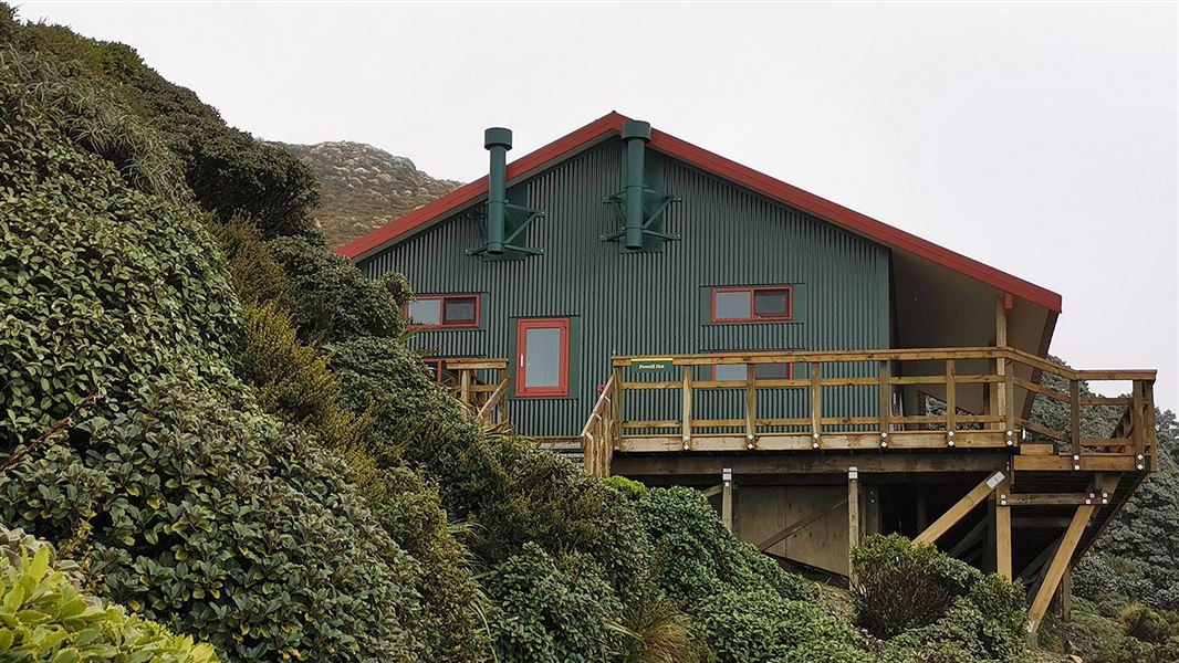 Single story building on side of hill with shrubs.