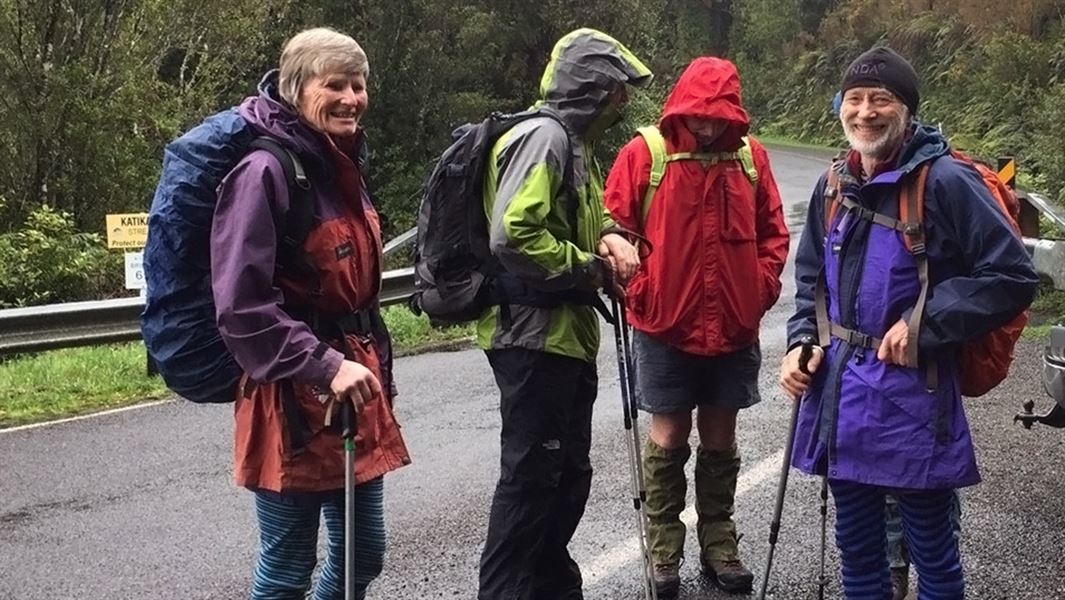 Four people, two facing the camera, dressed in hiking gear and smiling at the camera.