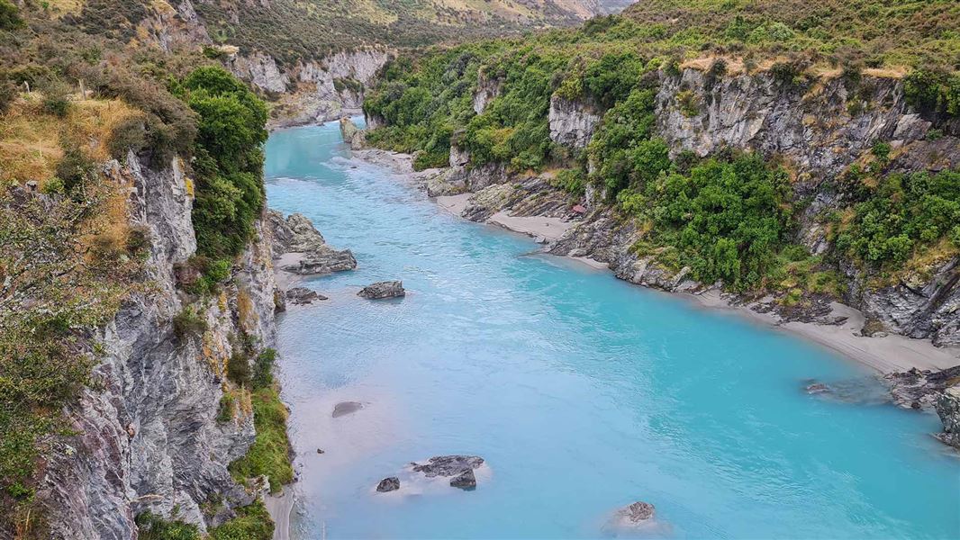 Sunny view looking down Rakitata gorge with bright blue crystal clear water.