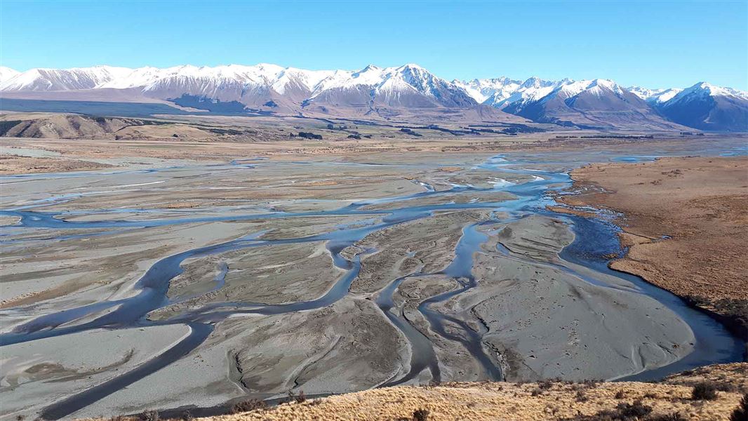 Small streams criss cross over sand in a valley flanked by mountains.