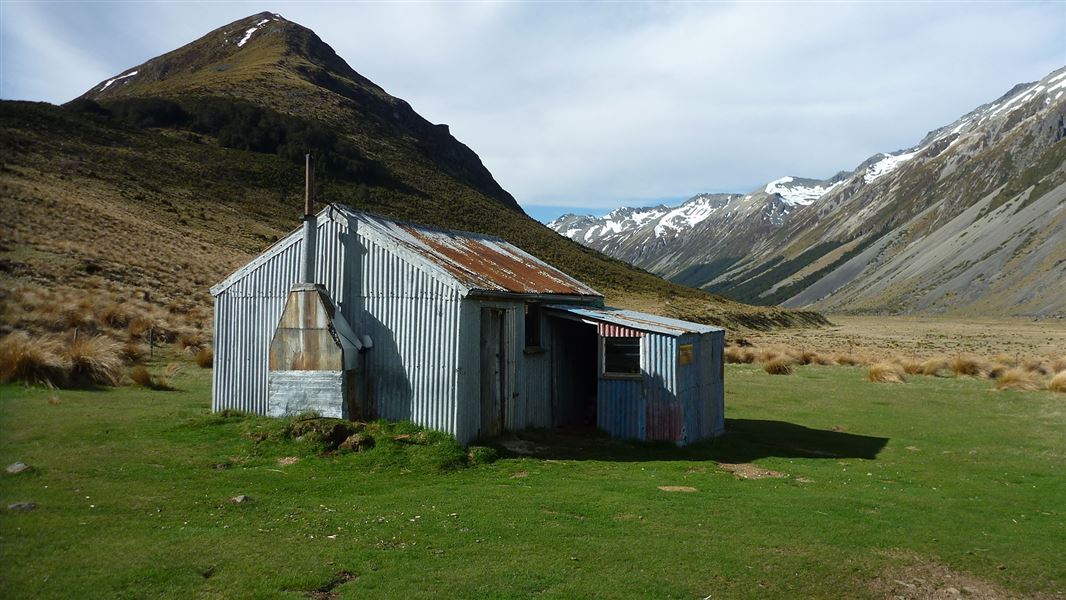 Small tin building near mountains.