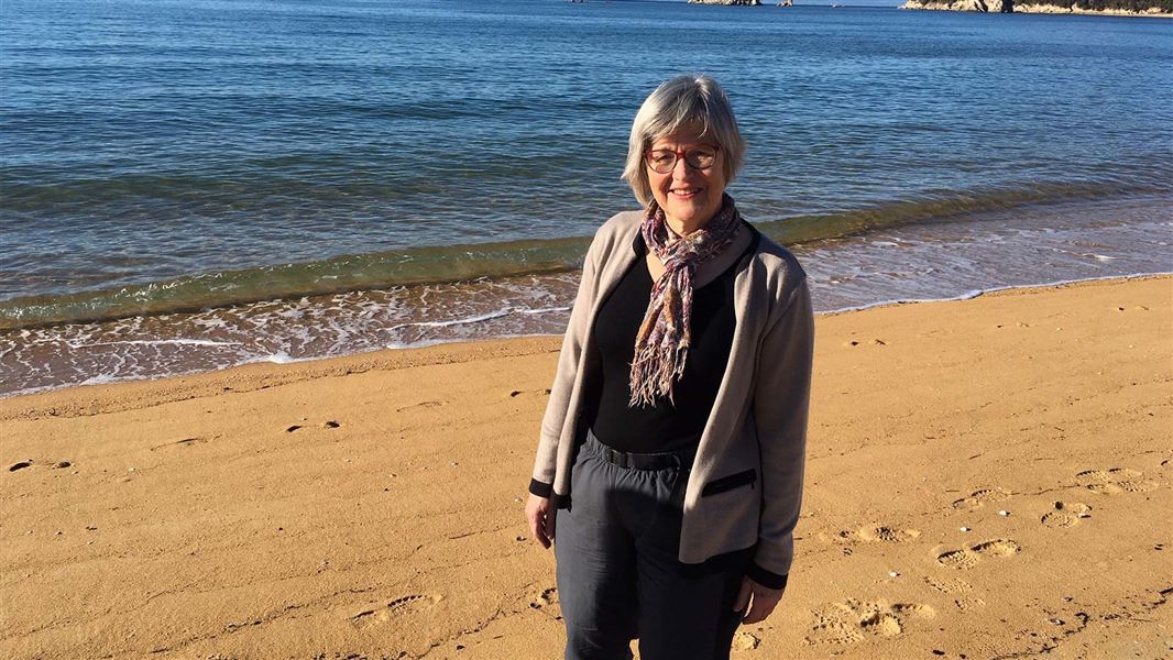 Woman with grey hair on a sandy beach.