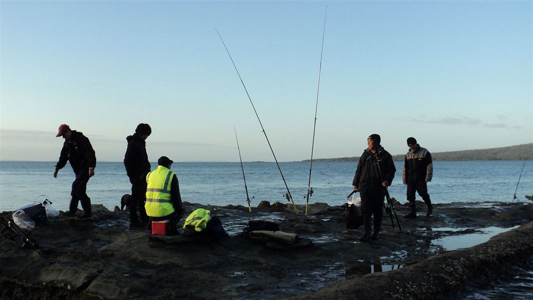 a group of men fishing on rocks.