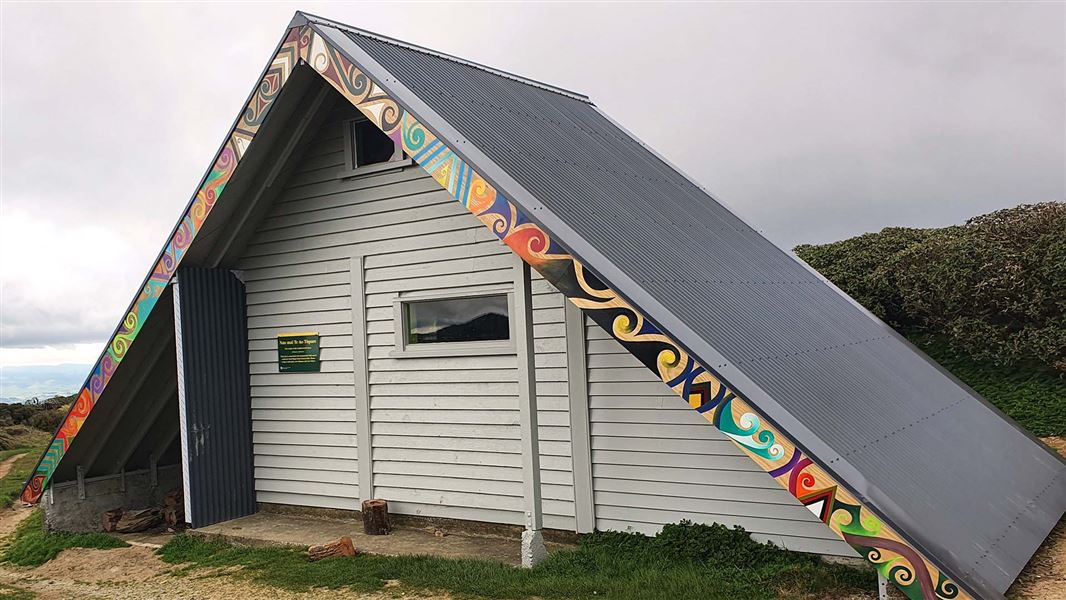 A triangular hut with a roof that goes down to the ground.