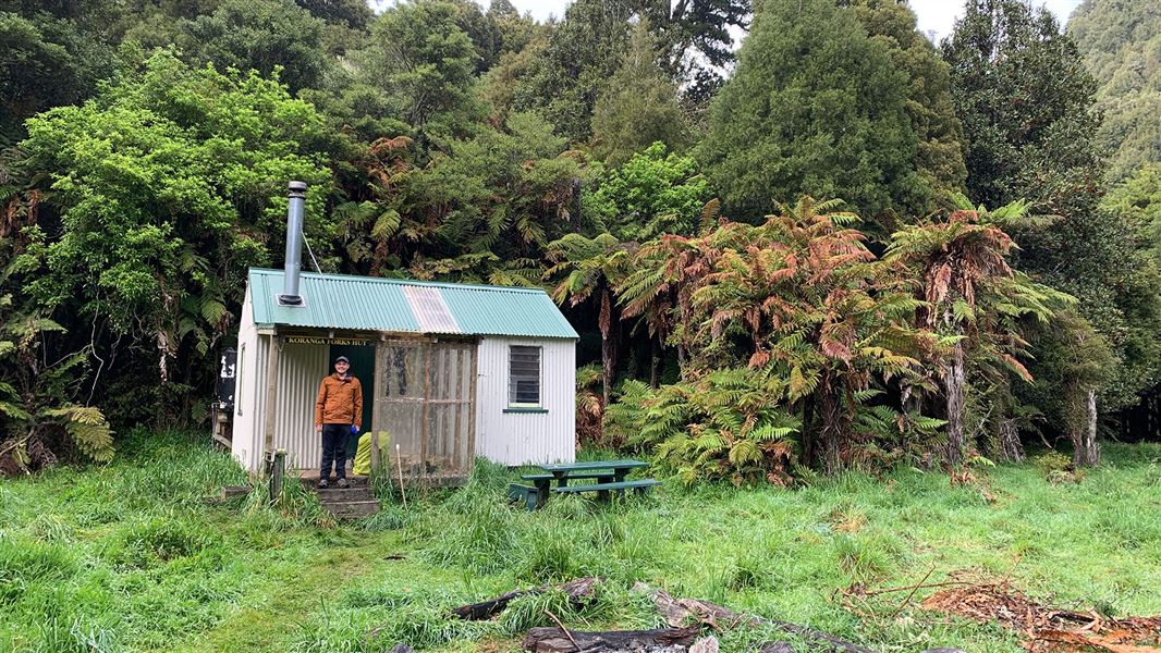 Person standing by small building.