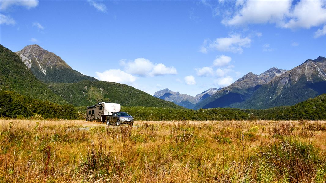 Grassy campsite by hills.