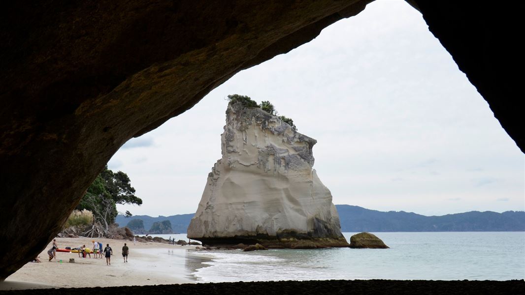 A view of the beach, framed by a hole in a cliff.