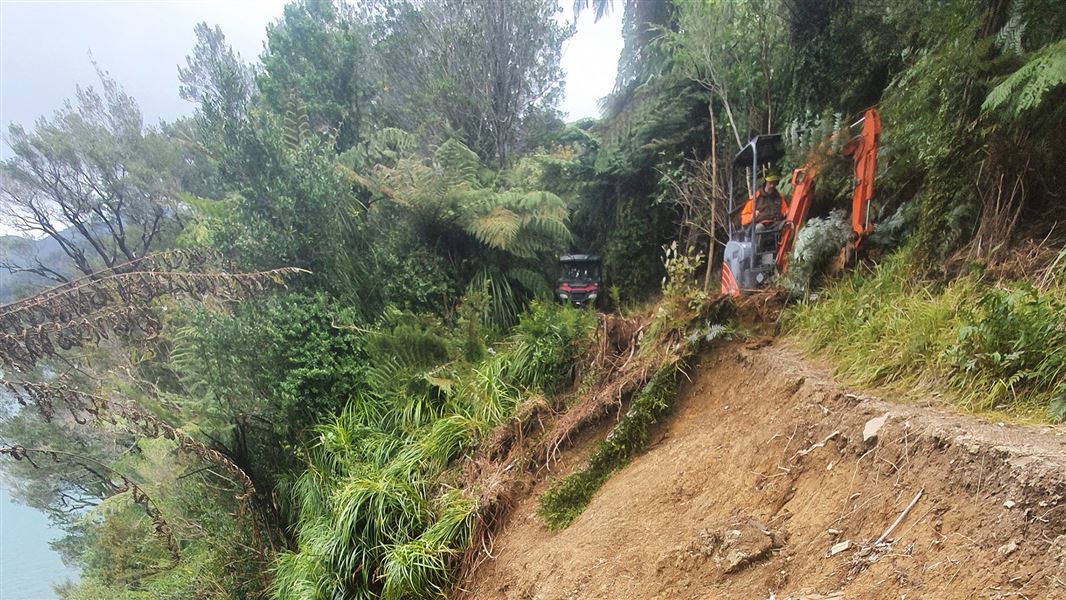 Person on digger clearing track.