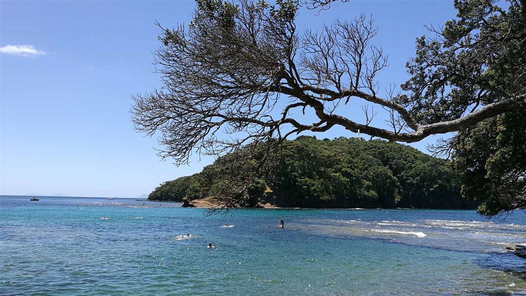 View out to island with blue ocean and snorkelers.