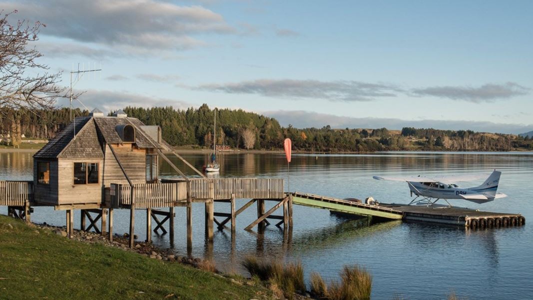 An image of the lake's edge showing the jetty with the floatplane moored nearby.