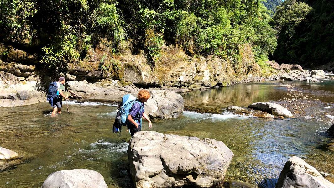 Two trampers walking in the river. 