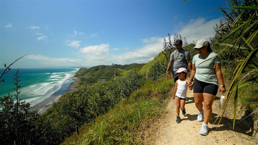 A family walking along a cliff track with sweeping views of the coastline below.