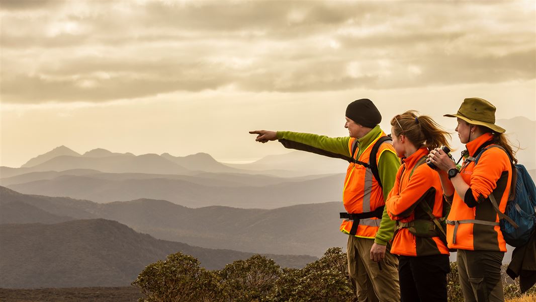 Picture of DOC staff on hills pointing into the difference.