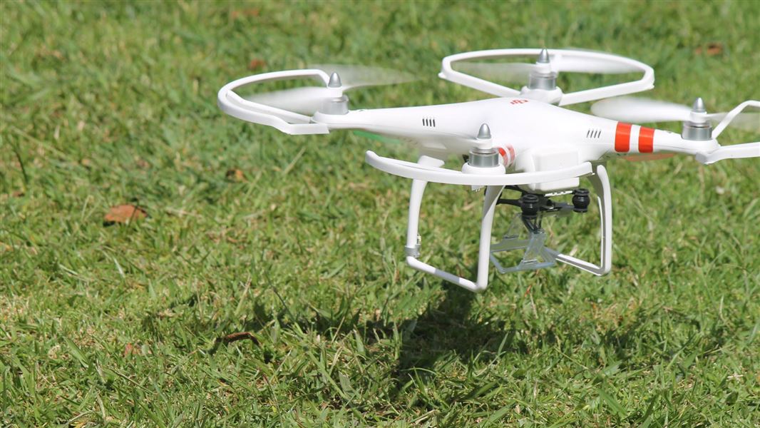 A drone taking off from a grassy area.