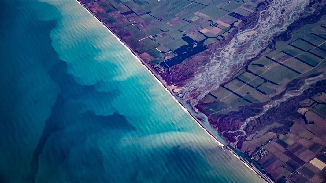 Aerial photo of dirty water flowing from a river into the sea.