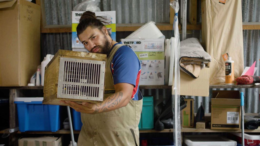 A person making a pest trap out of wood in a workshop.