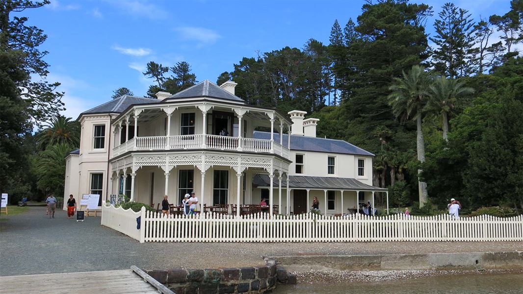 People explore outside of a white two storey large house.