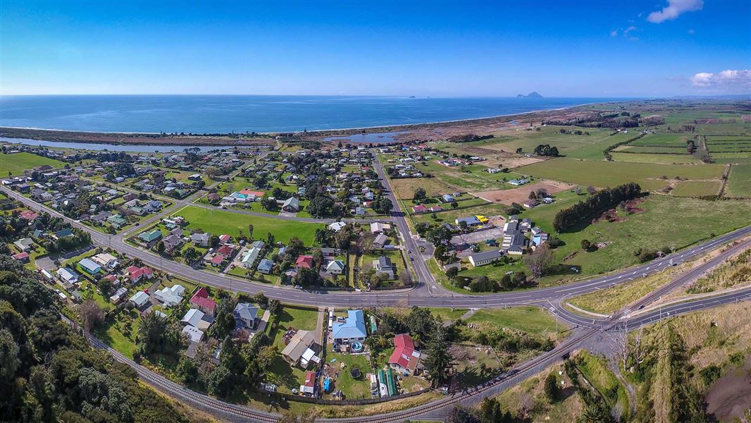 Aerial photo showing a small town on the seaside. Two islands can be seen far off in the distance.