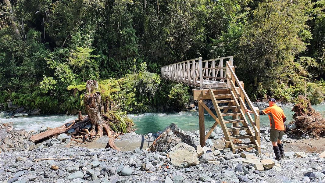 DOC worker looking over a wooden bridge in Fiordland.