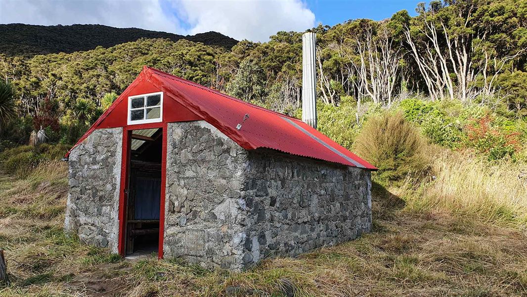 View of a stone hut with a red roof.