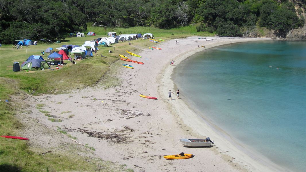 Children play among tents that sit on the edge of an inlet. It's a very bright day.