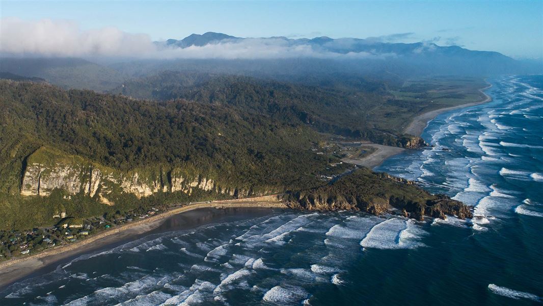 View of rugged and forested coastline from the air.